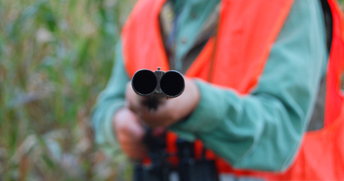 Jäger zielt mit seinem Gewehr in die Kamera des Fotografen